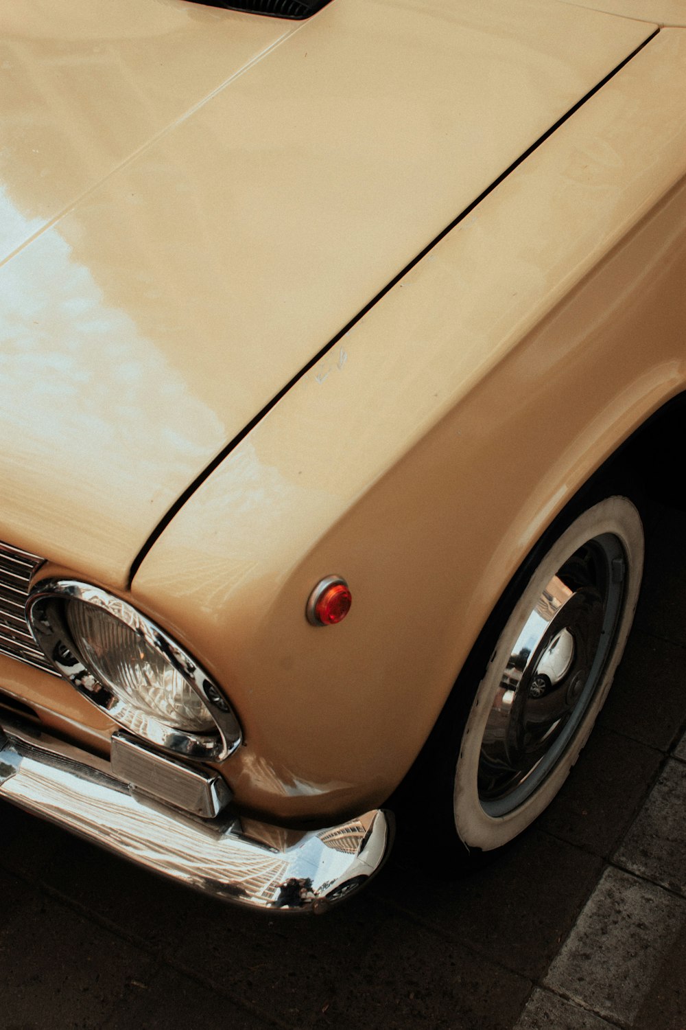 the front end of an old car parked on the side of the road