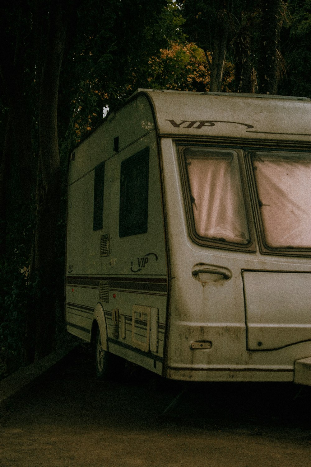 an old camper parked next to a tree