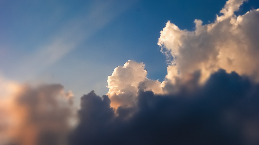 a plane flying through a cloudy blue sky