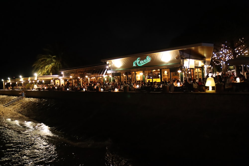 a group of people standing outside of a restaurant at night