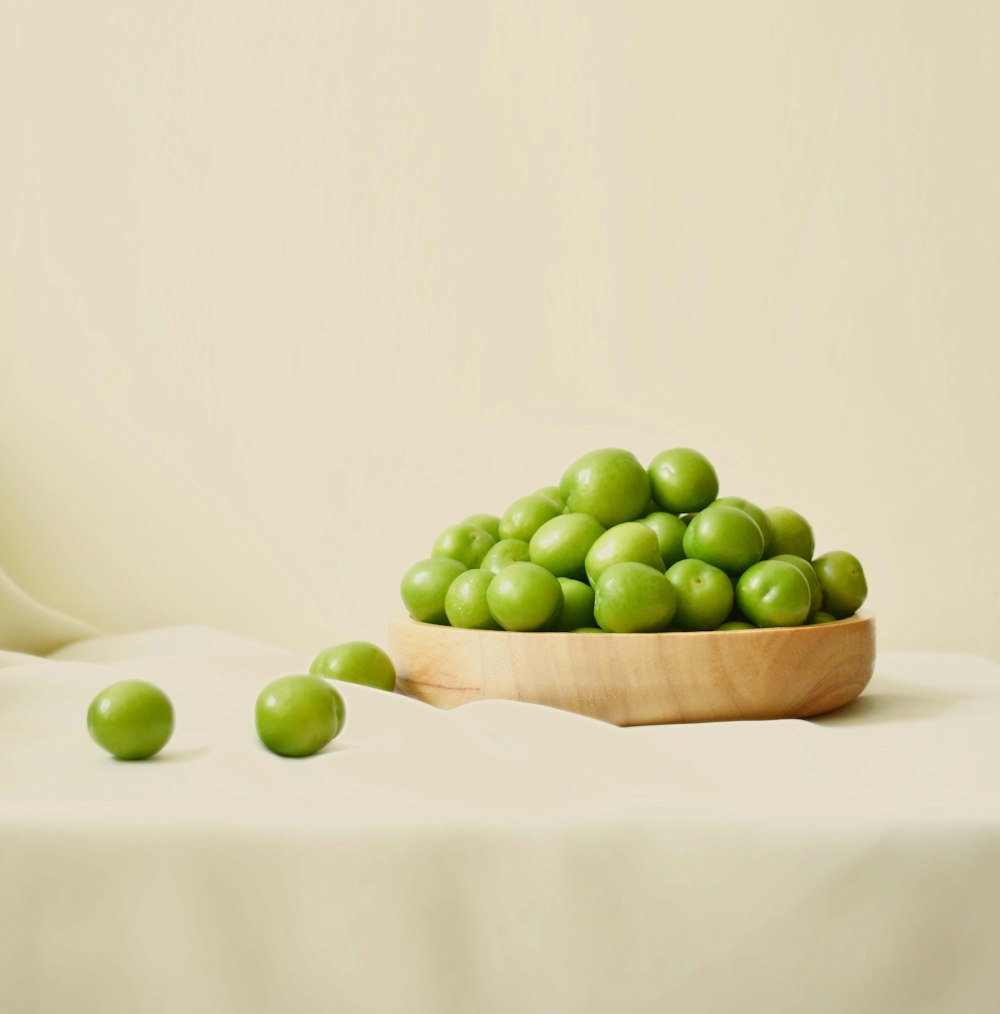 a wooden bowl filled with green peas on a table