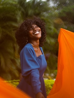 a woman smiling and holding an orange cloth