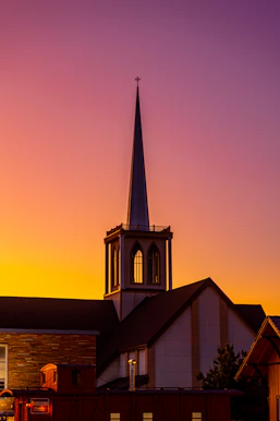 a church with a steeple at sunset