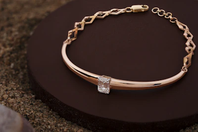 A delicate rose gold bracelet resting on soft olive green fabric, highlighting minimalist elegance.