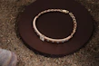 Elegant gold bracelet resting on a textured black surface reflecting warm light