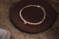 A stunning gold bracelet draped over a smooth stone surface.