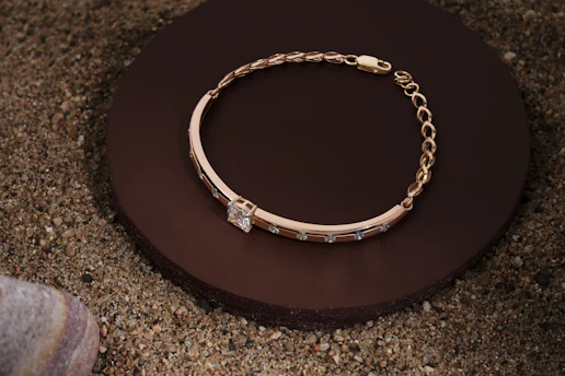 Elegant gold bracelet with personalized engraving resting on a wooden surface.
