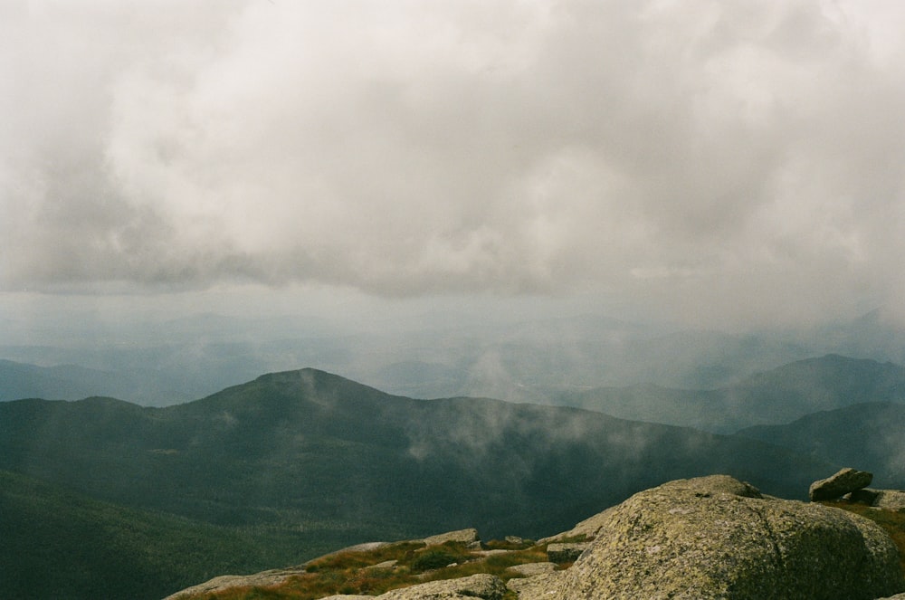 a person sitting on top of a rock on top of a mountain