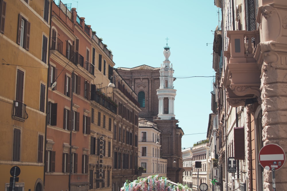 a narrow city street with a church steeple in the background