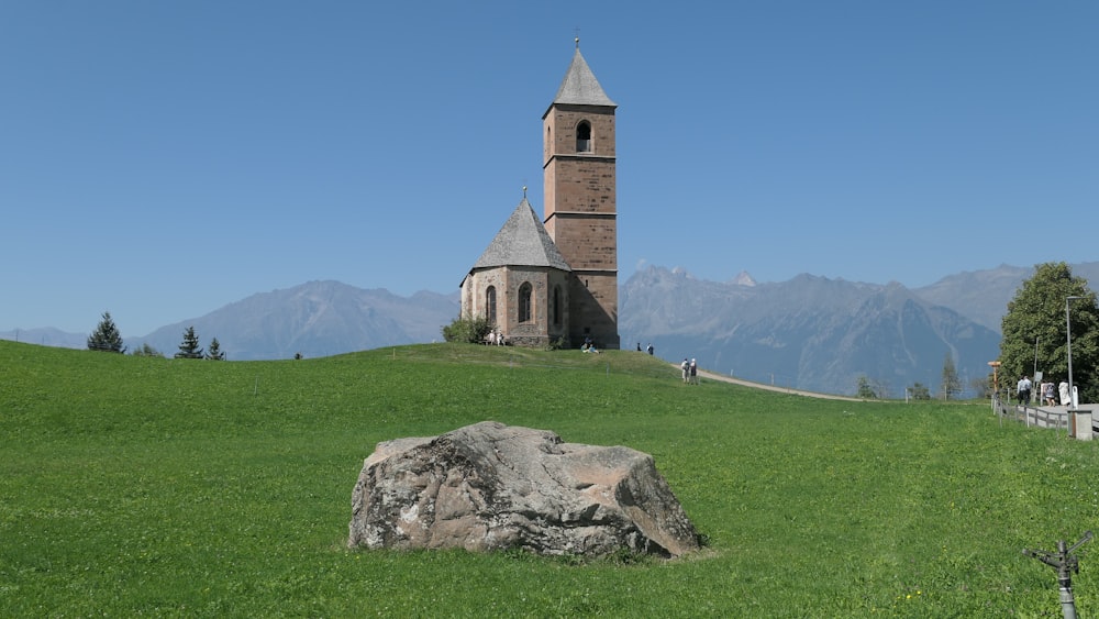 a church on a hill with a large rock in the foreground