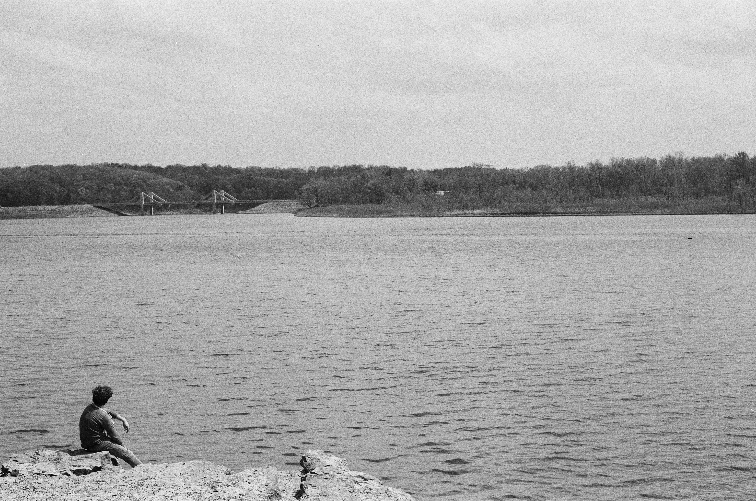 a man sitting on a rock near a body of water