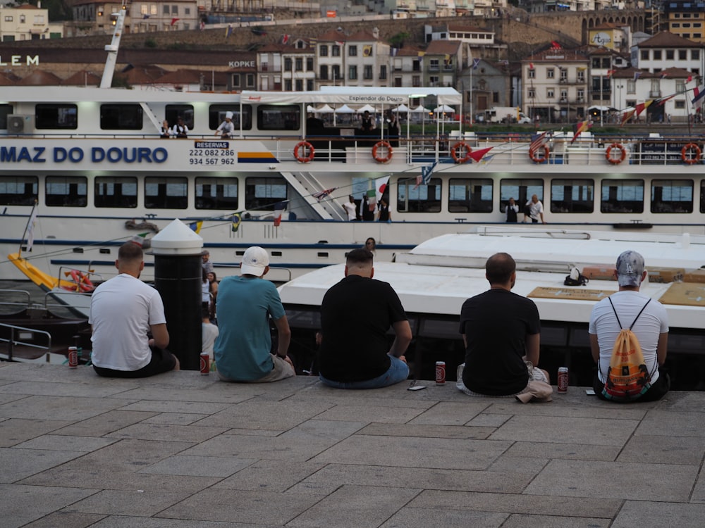 a group of people sitting on a dock next to a boat