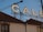 A large sign featuring the word 'CALE' is placed on top of a building with a tiled roof. A construction crane is visible in the background against a clear blue sky. Part of the building facade shows an arched window.