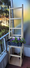 A sleek metal shoe rack with multiple tiers in a modern balcony setting.
