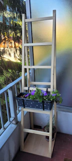 A sturdy, wobble-free shelving system holding plants and books on a sunny balcony.