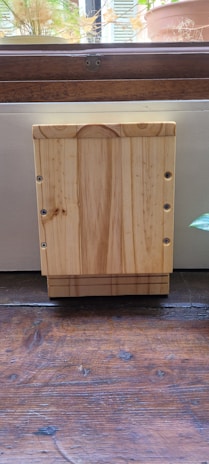 An ecostash box open with neatly arranged items inside, placed on a wooden shelf surrounded by plants.