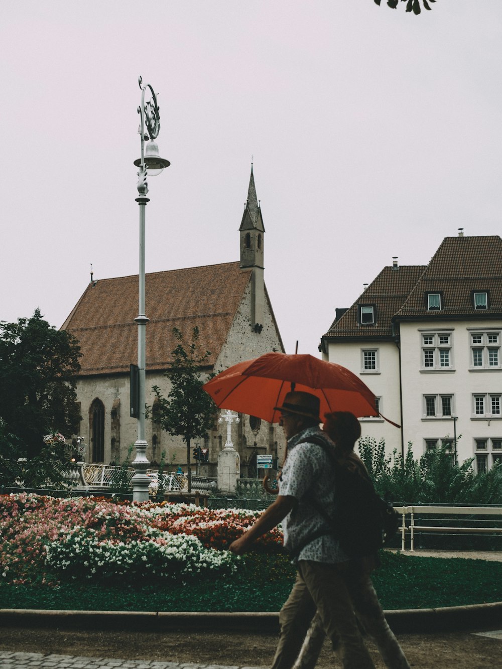 a man walking down a street holding a red umbrella