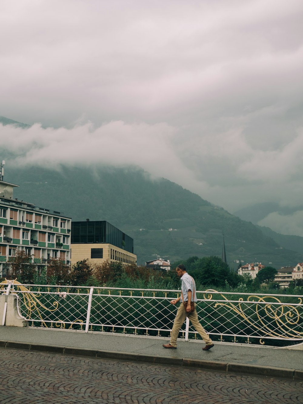 a man walking across a bridge next to a tall building