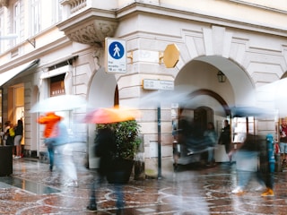 A vibrant street scene with blurred motion of people walking under colorful umbrellas.