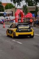 a yellow race car driving down a street