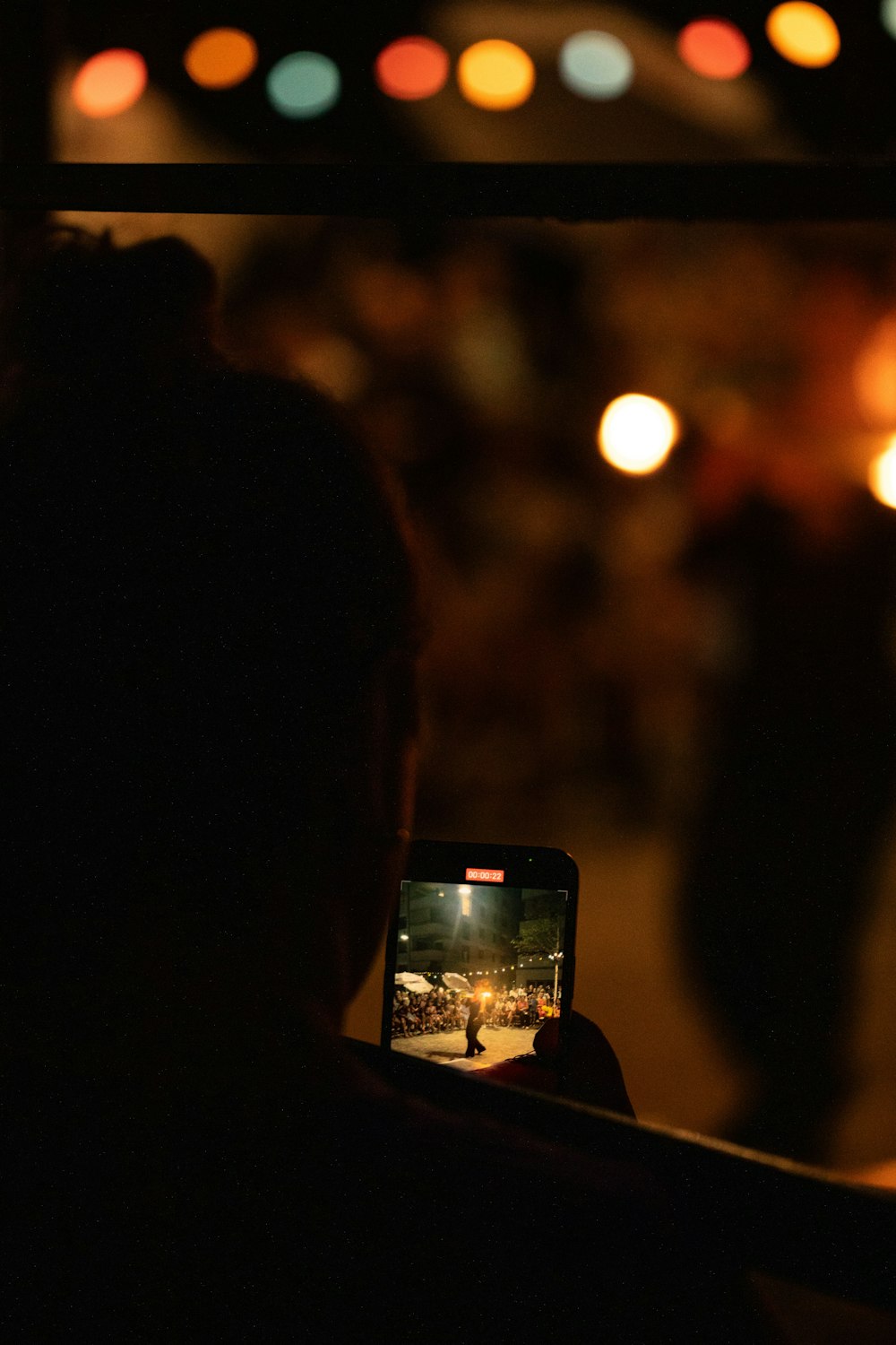 uma pessoa tirando uma foto de uma rua à noite