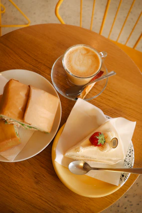 A warm cafe setting with a steaming cup of coffee and a chicken sandwich on a plate
