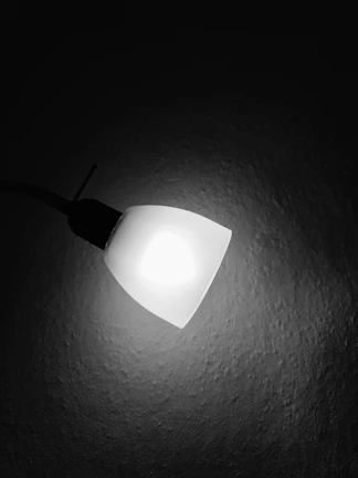 Close-up of a stylish spot light highlighting an elegant art piece against a clean white wall.