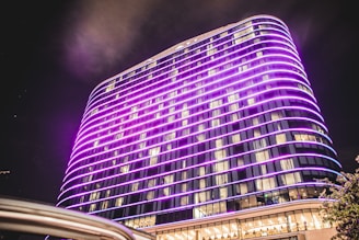 A sleek hotel exterior lit up in purple hues during the evening.