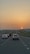 A sunset view over a highway with cars traveling in both directions.