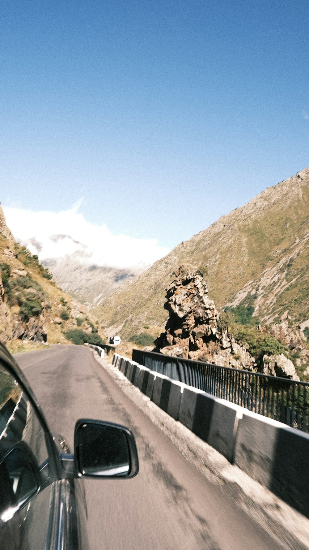 um carro dirigindo por uma estrada ao lado de uma montanha