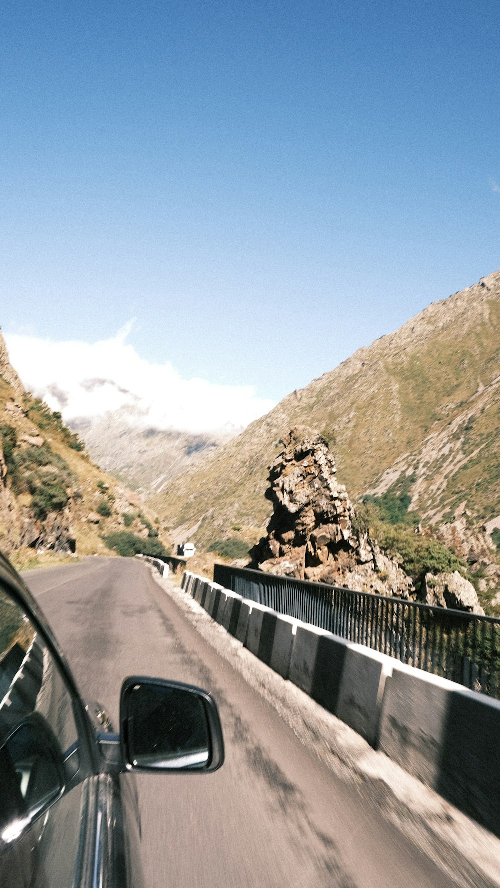 a car driving down a road next to a mountain