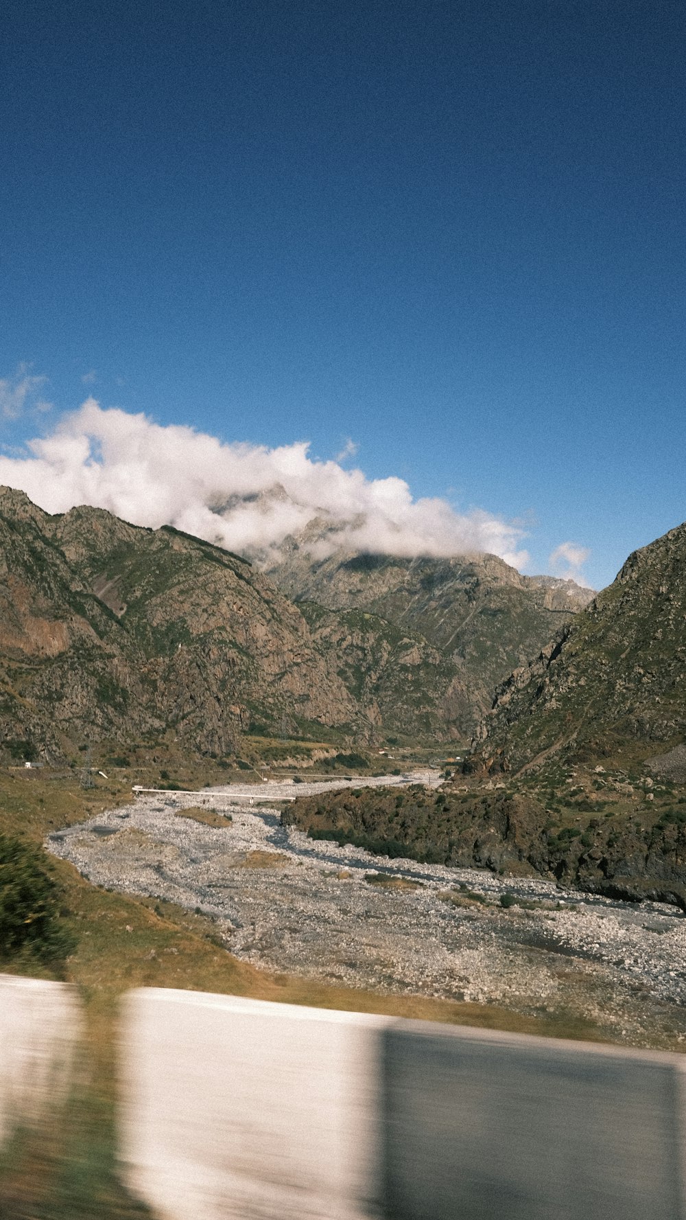 a view of a river and mountains from a moving vehicle