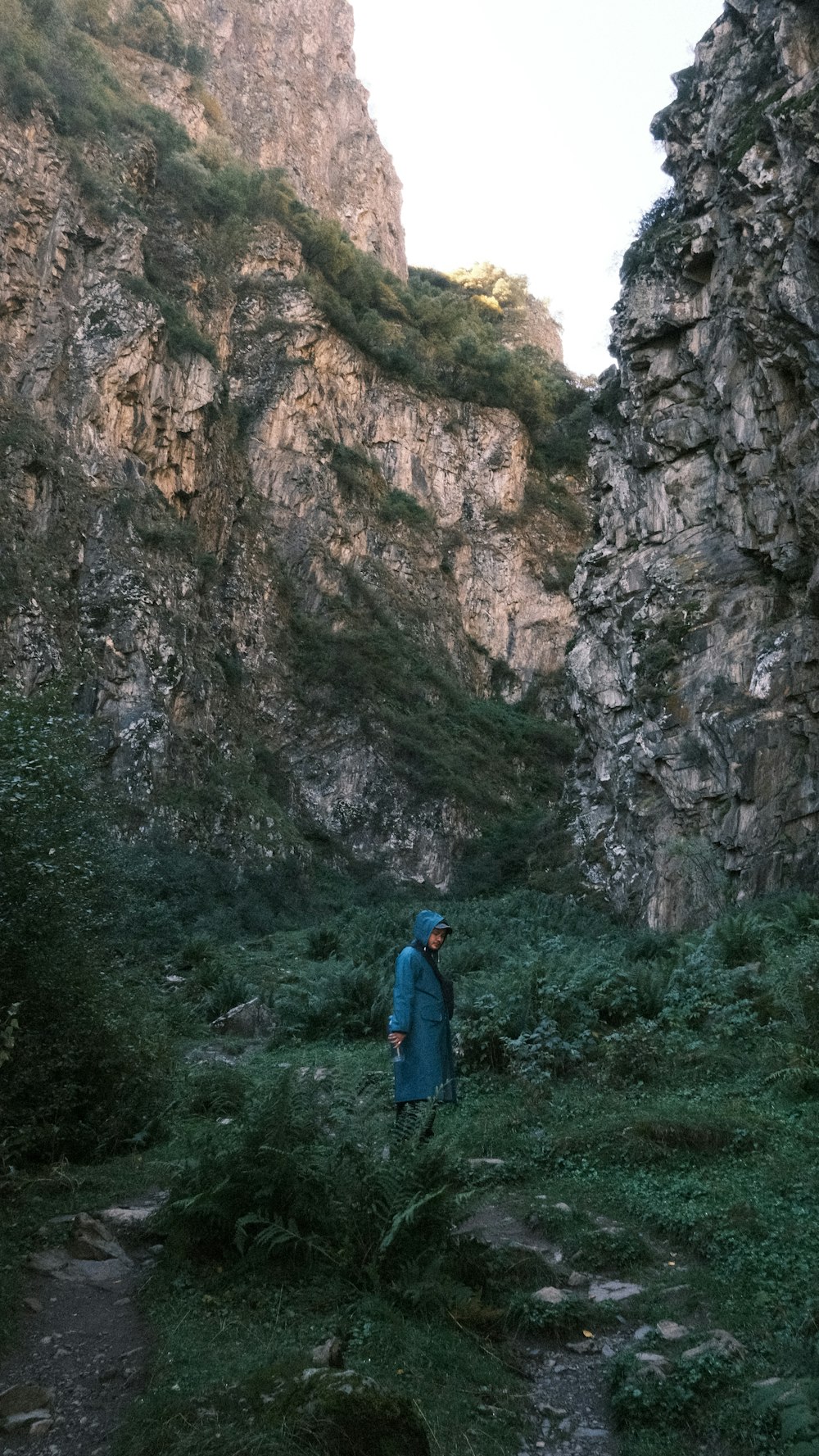a person in a blue coat standing in a rocky area