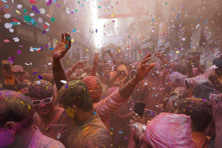 a group of people celebrating with colored powder and confetti