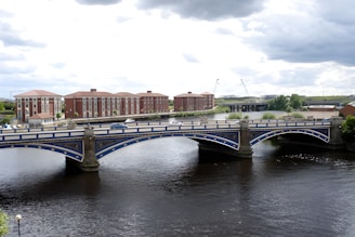 a bridge over a river with buildings in the background