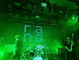 Rina Kelly performing softly on stage with a minimalist backdrop.