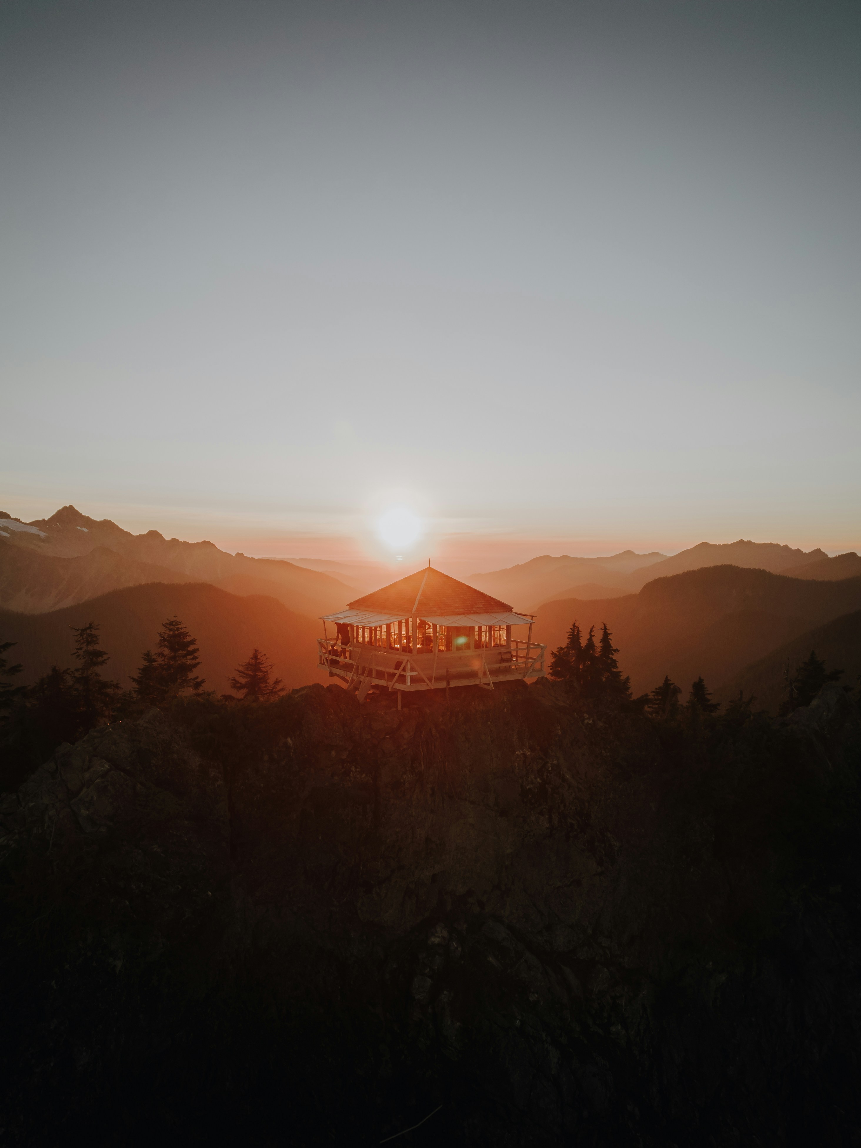a gazebo sitting on top of a mountain at sunset