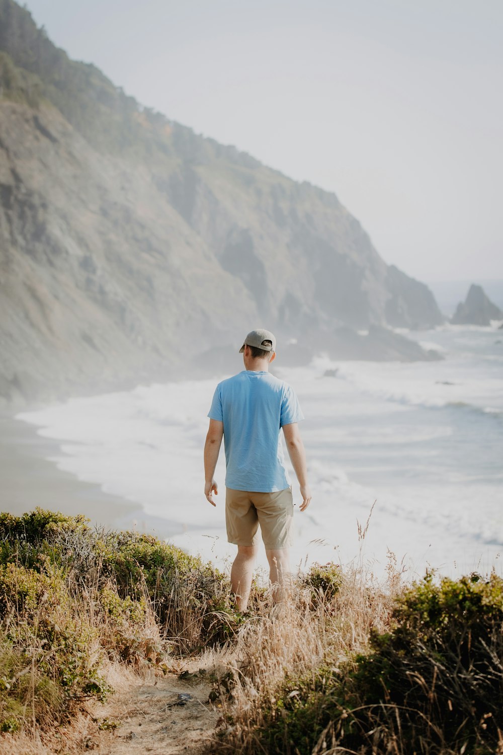 a man walking up a hill towards the ocean