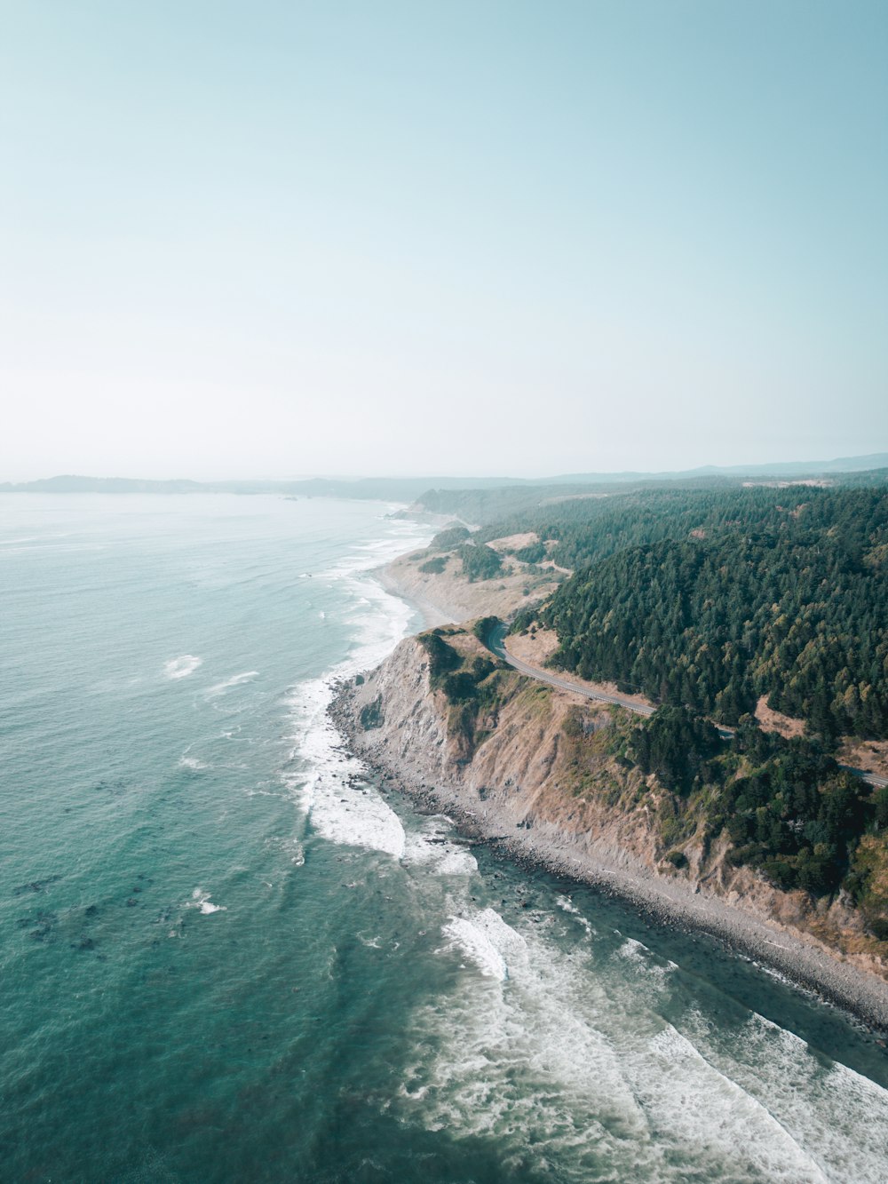 an aerial view of the ocean and a road