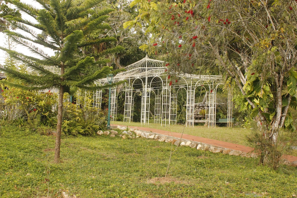 a garden with a white gazebo surrounded by trees