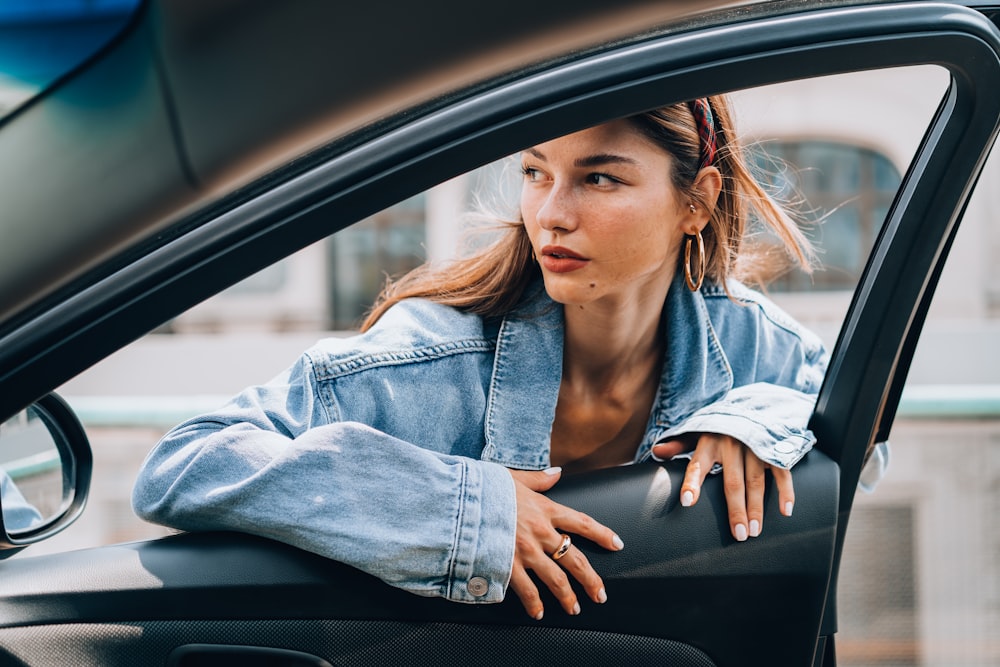 a woman sitting in a car looking out the window