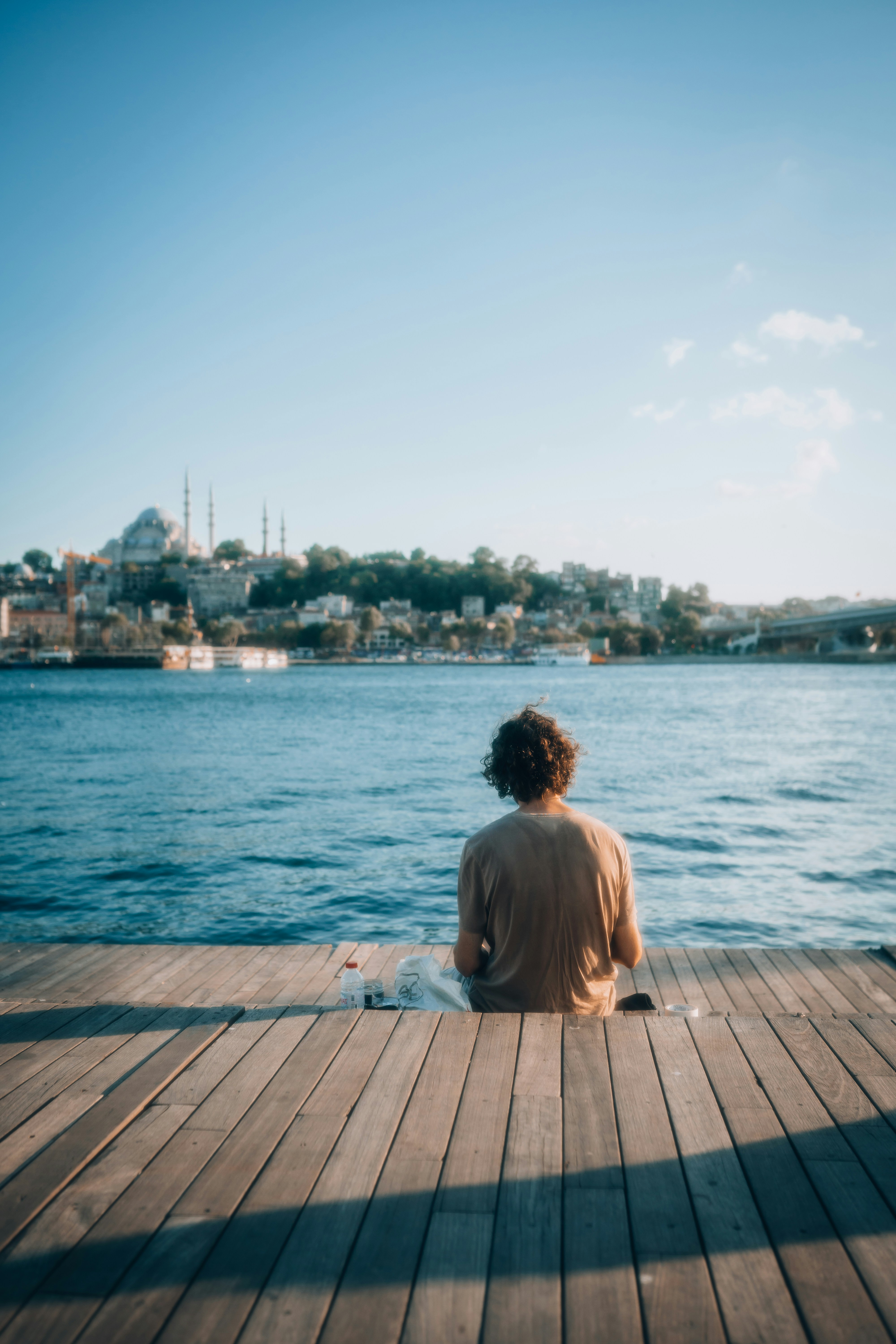 Una persona sentada en un muelle mirando el agua