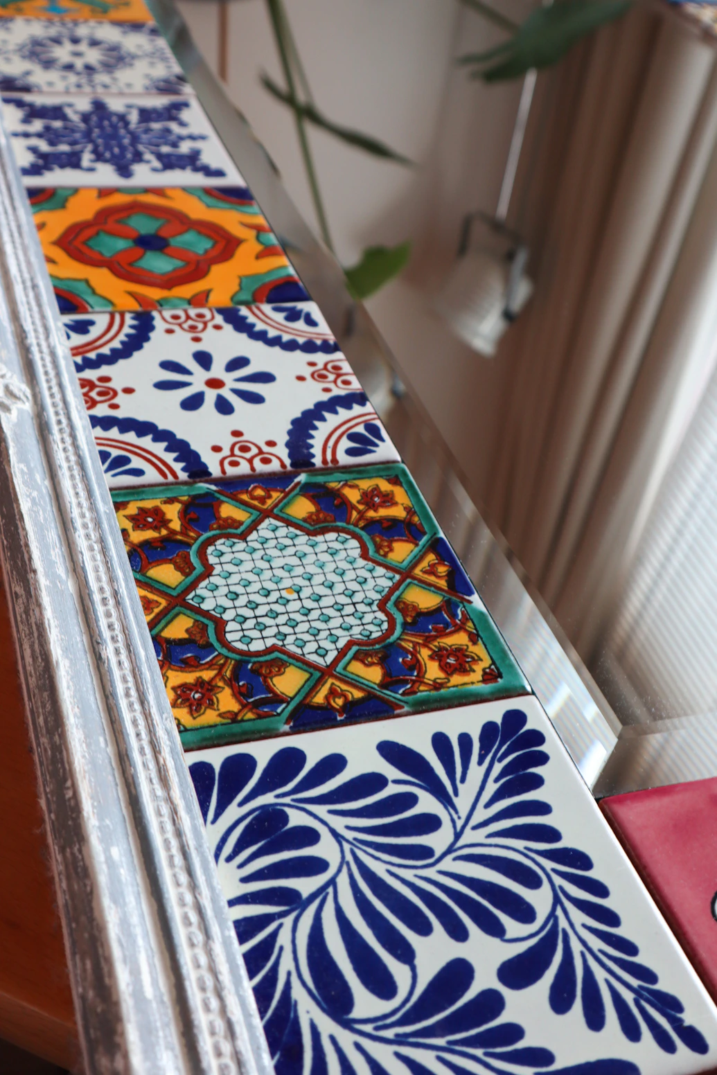 Close-up of elegant crimson ceramic tiles in a stylish indoor setting with natural wood and plants.