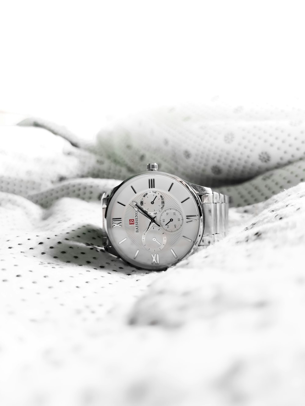 a watch sitting on top of a white blanket