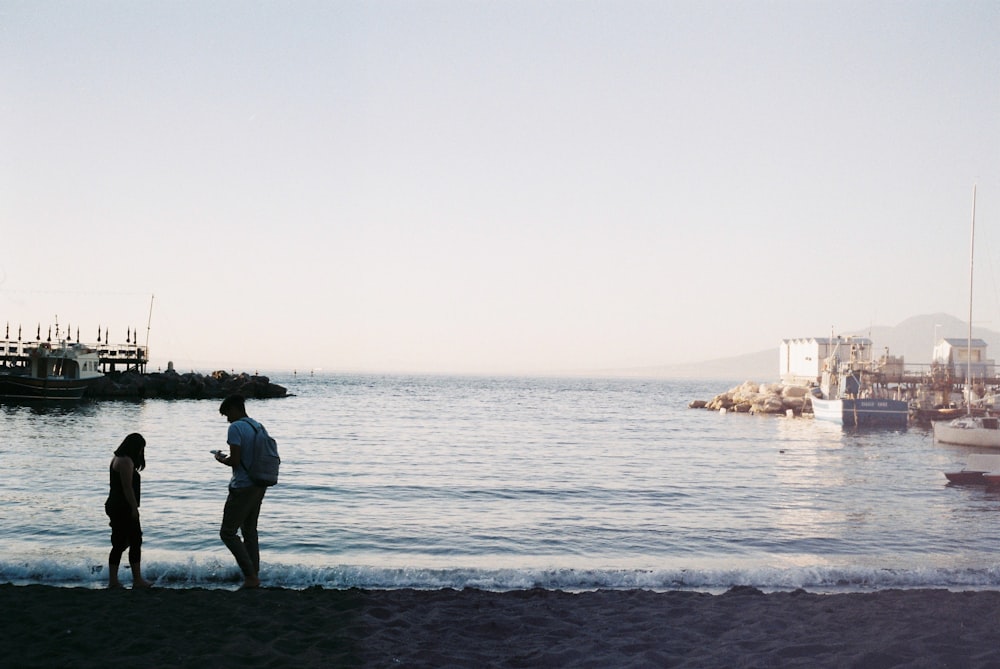 a couple of people standing on top of a beach