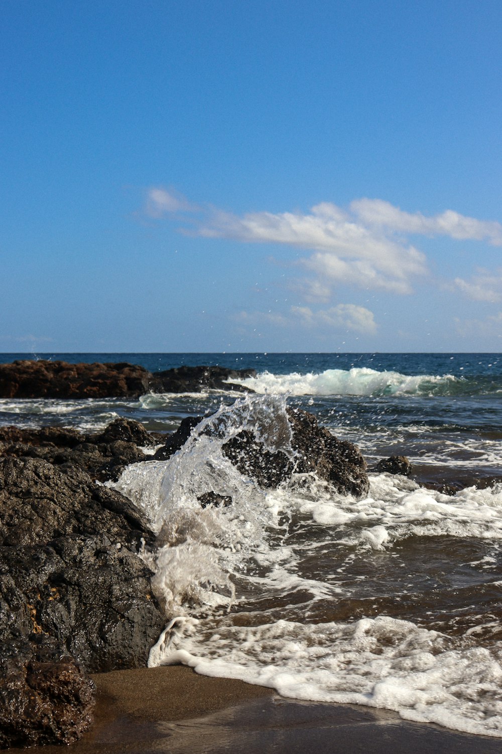 a person standing on a rocky beach next to the ocean