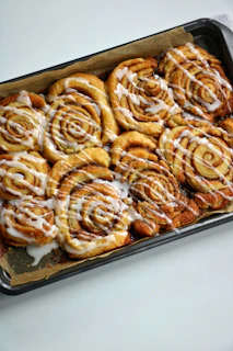 a pan filled with cinnamon rolls covered in icing