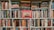 A densely packed bookshelf full of various books, with titles spanning multiple genres and topics. The centerpiece is a prominently displayed red book titled 'Titanic,' featuring an image of the ship. The books are of varying sizes and colors, showcasing a wide array of literary interests.