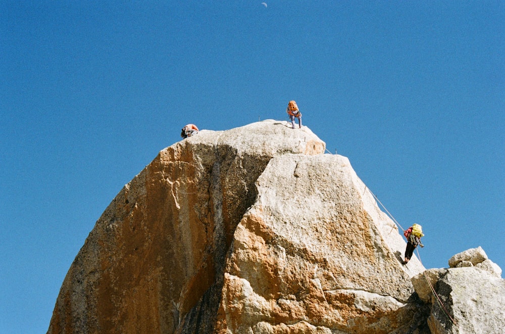 a group of people standing on top of a large rock