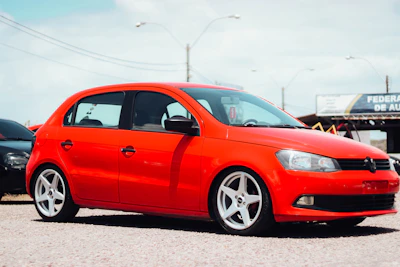 A bright red compact car ready for pickup at a sunny airport parking lot.
